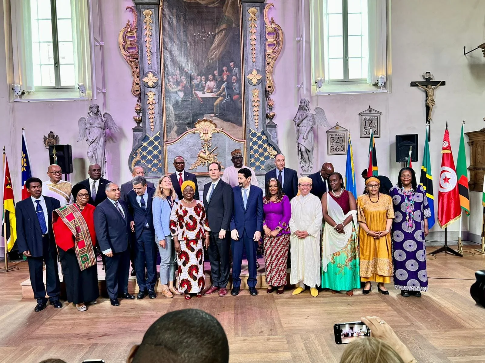 Ambassadors and guests in national dress lined up in front of the flags of African countries