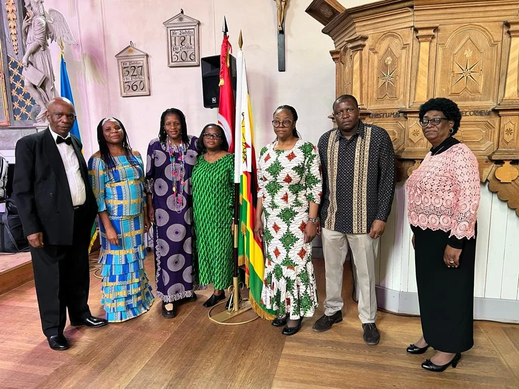 Guests in African dress standing in front of the flags