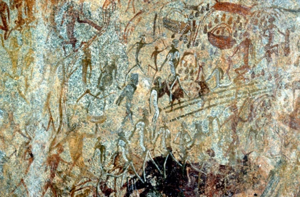Ancient rock paintings of people and animals on a rock face