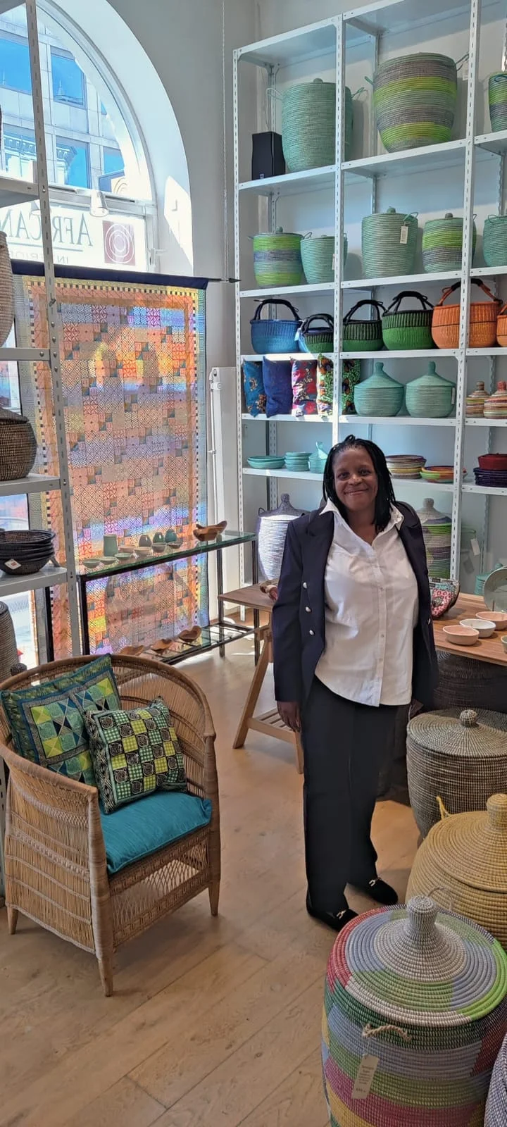 A woman in an African shop with shelves of crafts and homeware